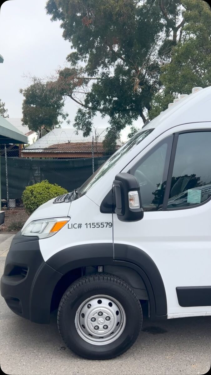 White Ram ProMaster van with cut vinyl graphics along the flank and a contractor licence number on the cab door