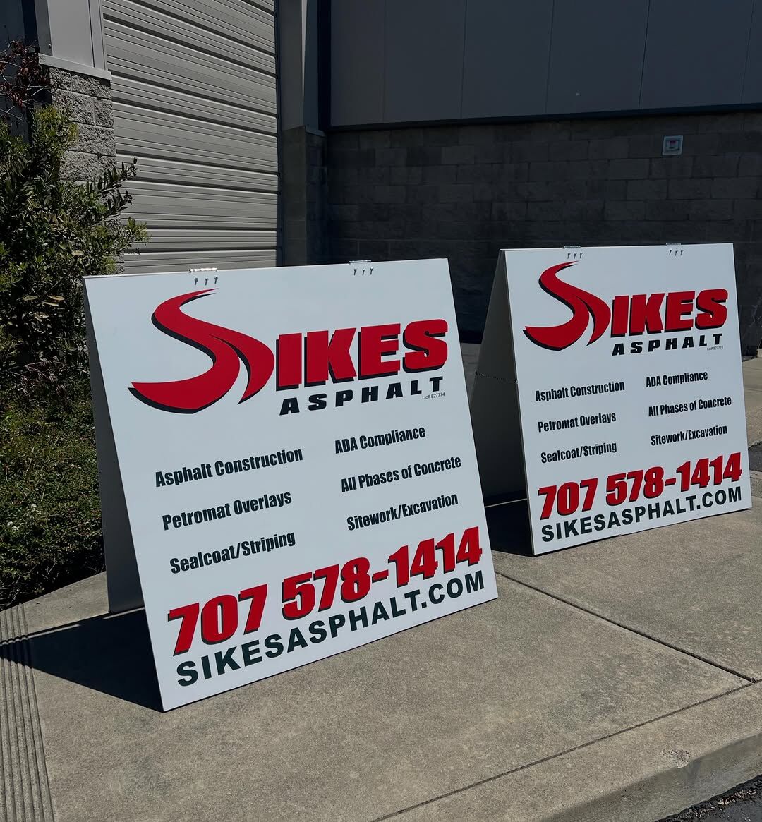 Two Sikes Asphalt A-frame signs in red, white and black listing services, a phone number and a website