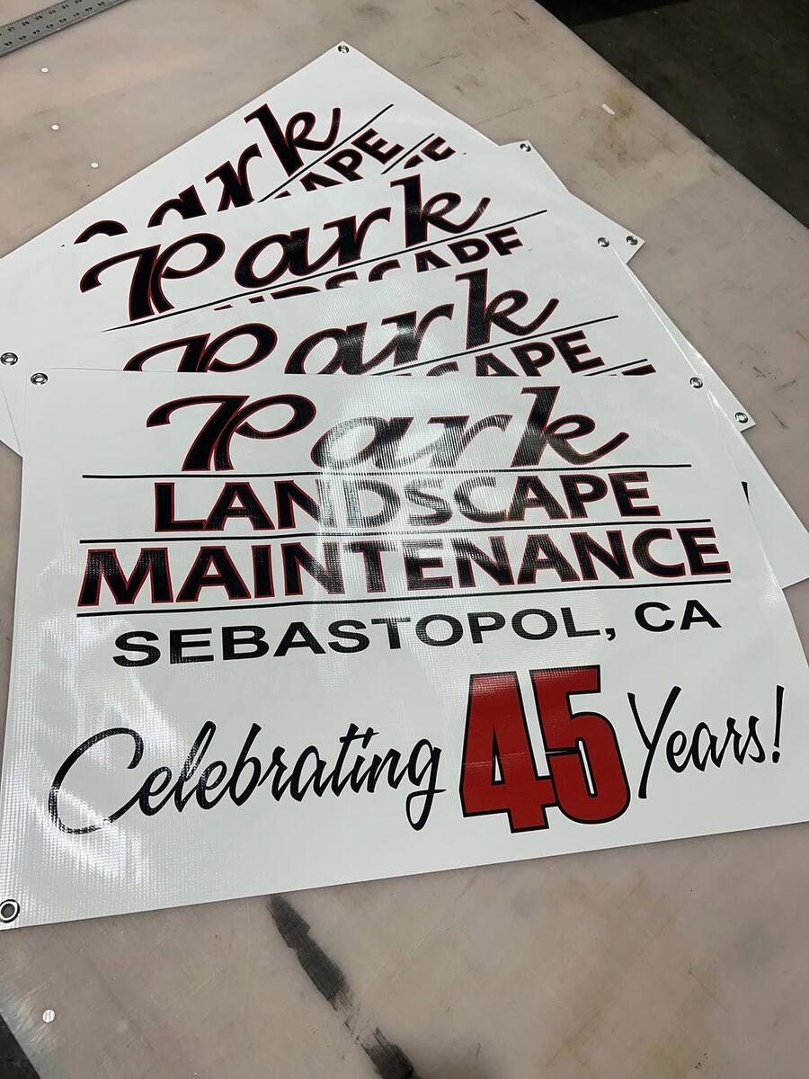 Cut vinyl lettering reading Park Landscape Maintenance, Sebastopol CA, Celebrating 45 Years, laid out before installation