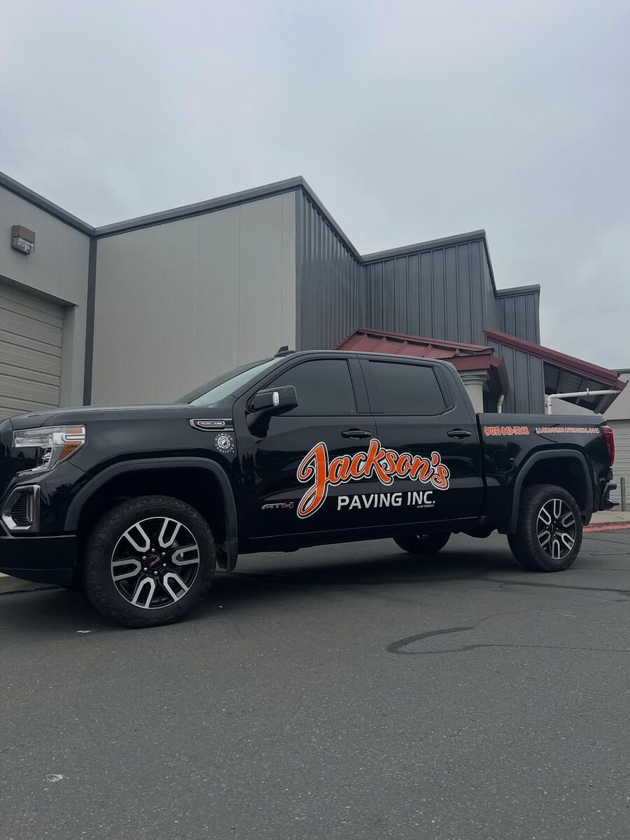 Black GMC pickup carrying the orange and white Jackson's Paving Inc mark across the door