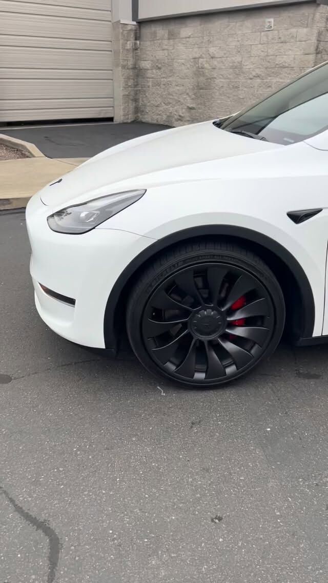 White Tesla Model Y photographed from the front three-quarter with black wheels