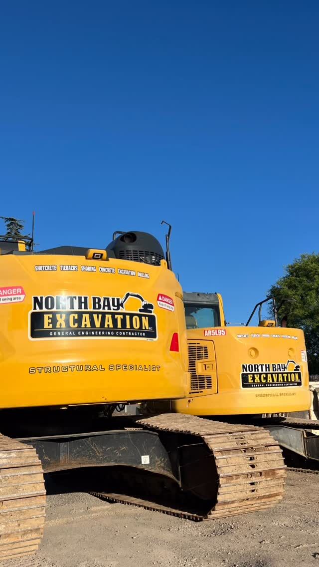 Yellow excavator carrying North Bay Excavation graphics on the boom and counterweight