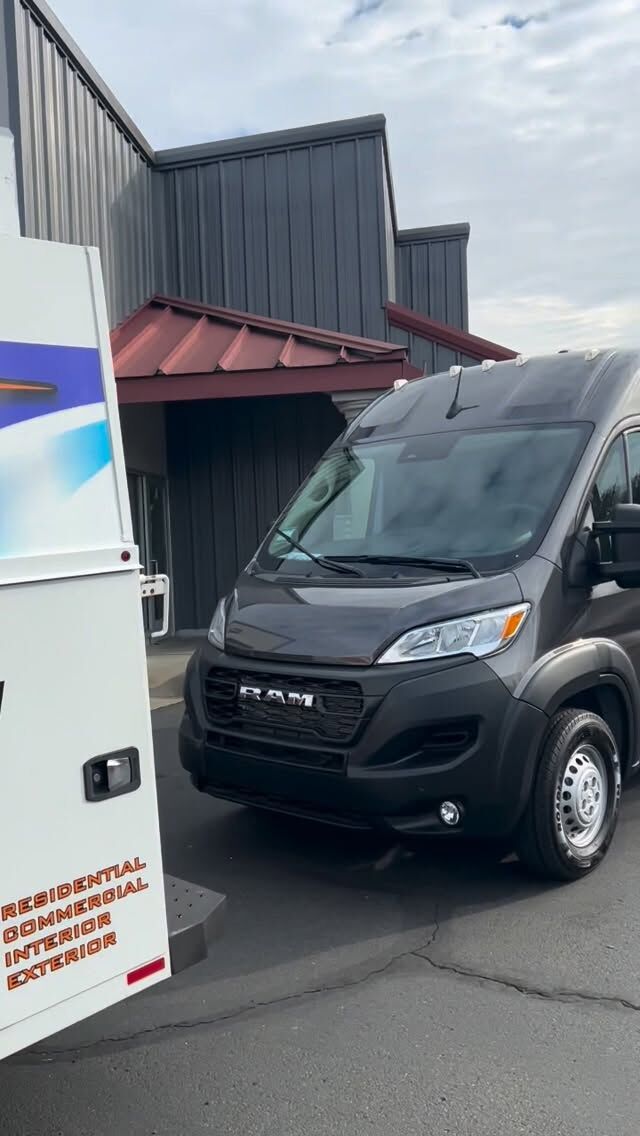 Dark grey Ram ProMaster high-roof van photographed from the rear three-quarter outside the shop