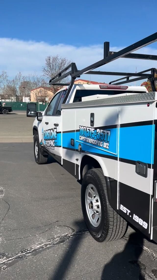 White utility service truck with a ladder rack and blue and grey graphics along the service body