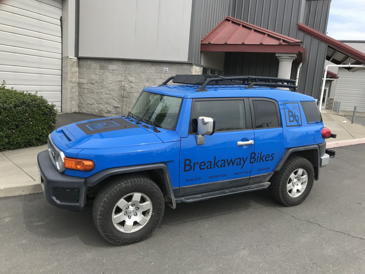 Blue Toyota FJ Cruiser carrying dark blue Breakaway Bikes graphics along the doors
