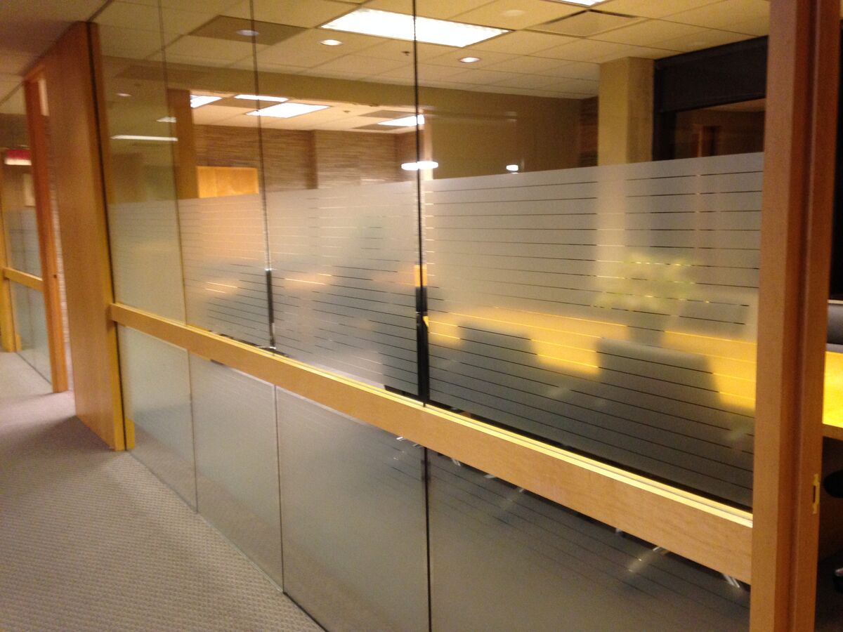 Office glass partition banded with graduated frosted vinyl stripes that screen the room at seated height while daylight still passes through