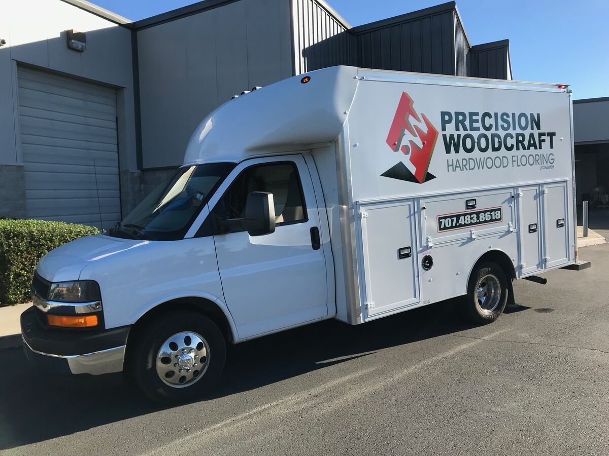 White service box truck carrying the Precision Woodcraft Hardwood Flooring mark and phone number on the box side