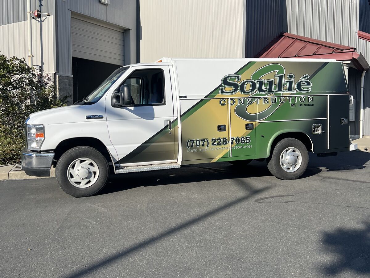 White Ford box van for Souli&eacute; Construction, the service body carrying a green and gold diagonal sweep with the script wordmark, licence number and phone across it