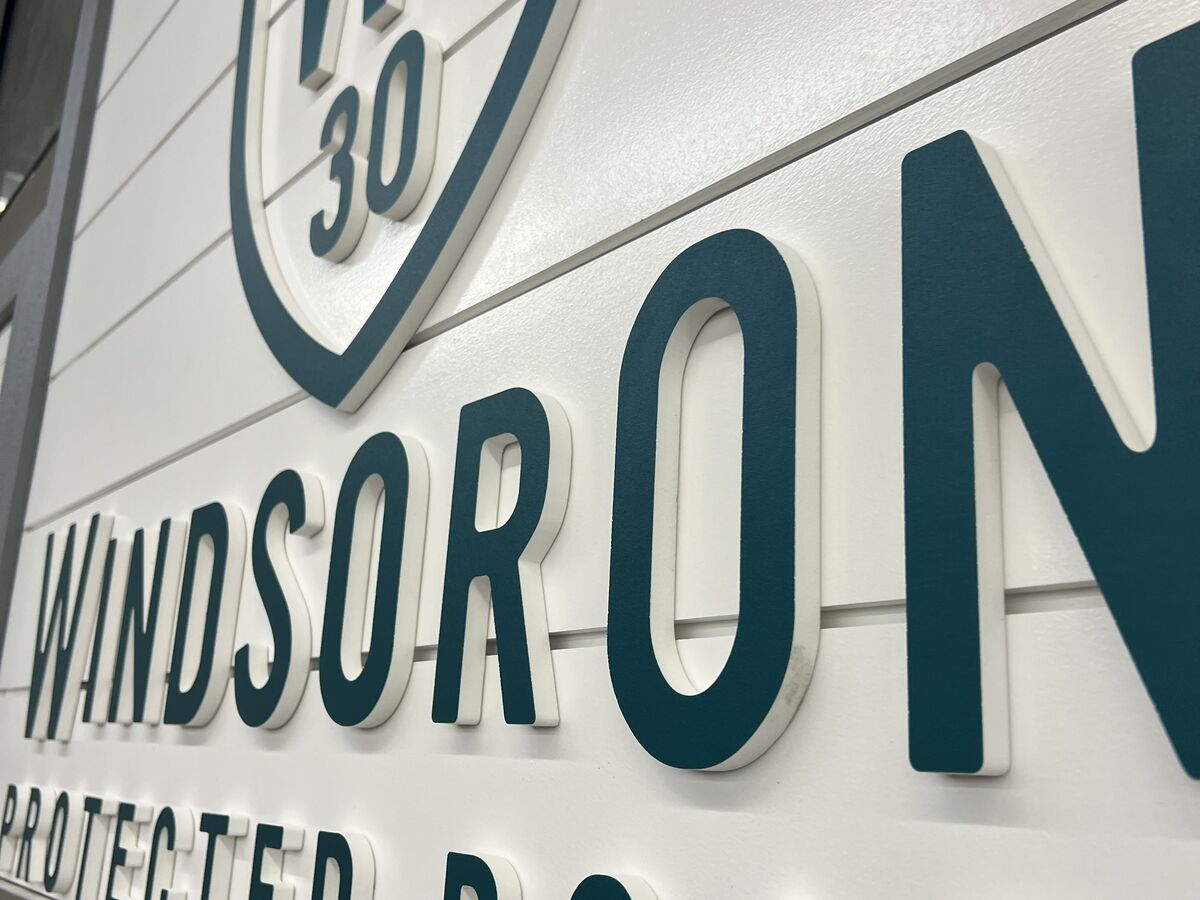 Raised dimensional letters reading Windsor Oaks Protected Board on a white panel, photographed from below so the letters cast a shadow